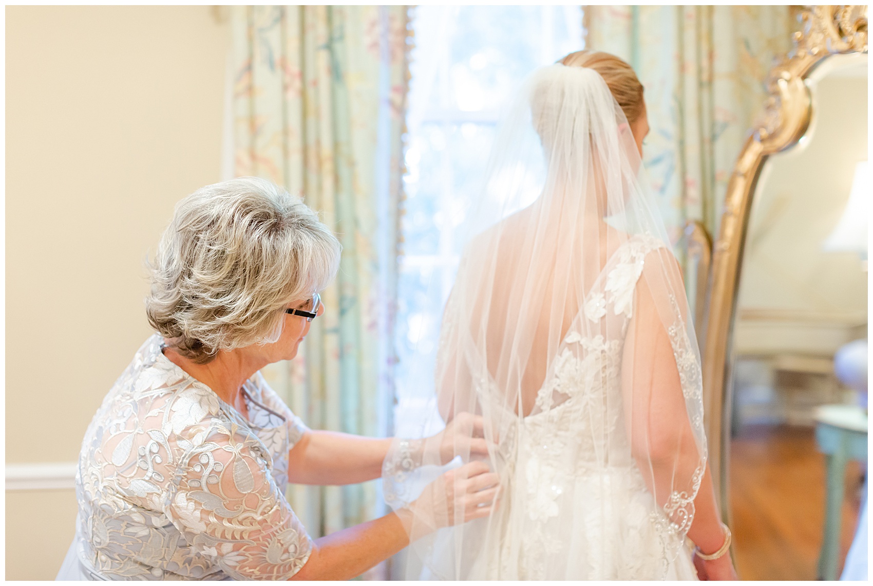 mother of the bride helps the bride to put on her dress for her charleston wedding